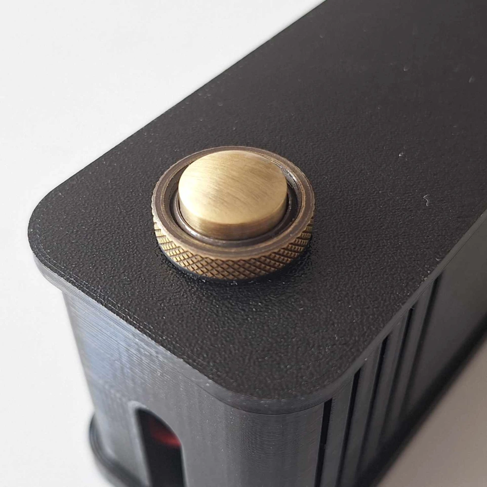 MOUNTME PowerCase mit bronzefarbenem Taster, Nahaufnahme des schwarzen Kunststoffgehäuses